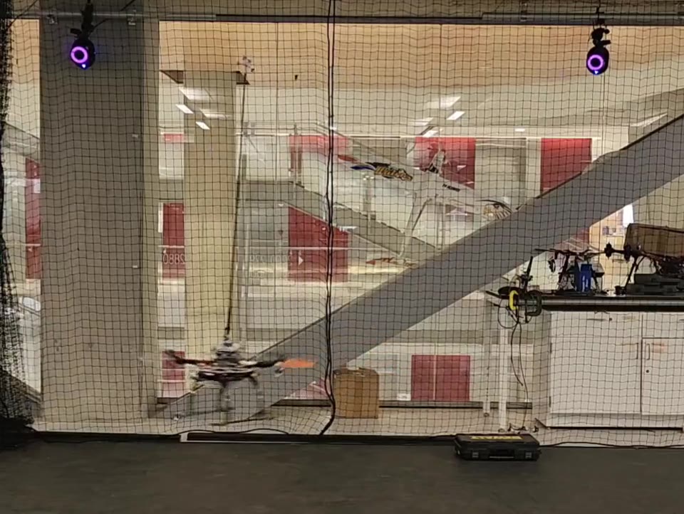 A quadrotor balancing an upright pendulum during an indoor flight experiment.